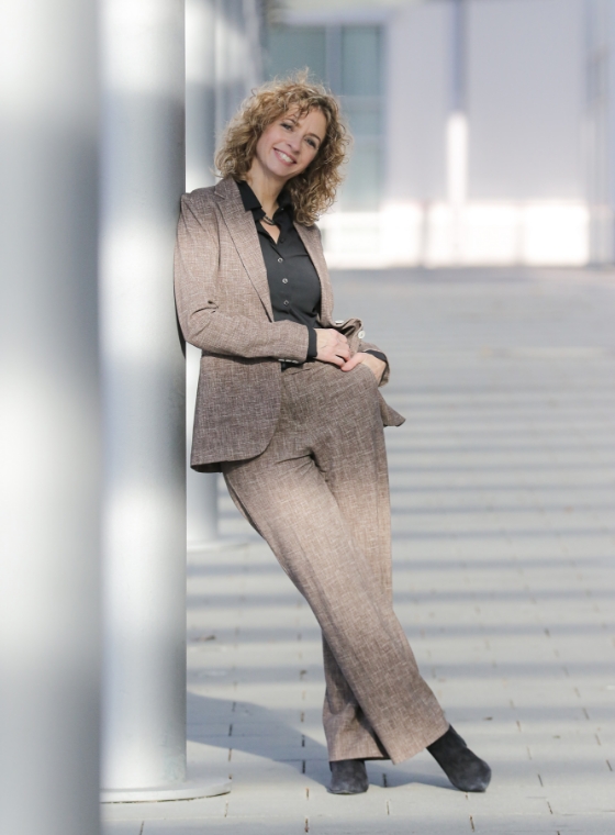 twin Werbeagentur | Business- und Imagefotografie | lächelnde Frau mit modernen braunen Anzug posiert in der Sonne